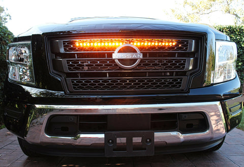 black nissan titan with one led light bar behind the grille in amber color for off roading