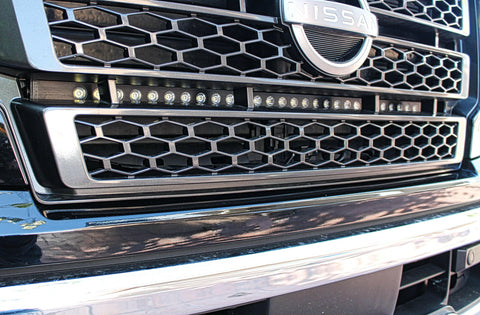 up close view of grille on nissan titan with one led light bar behind the grille in for off roading below the nissan logo