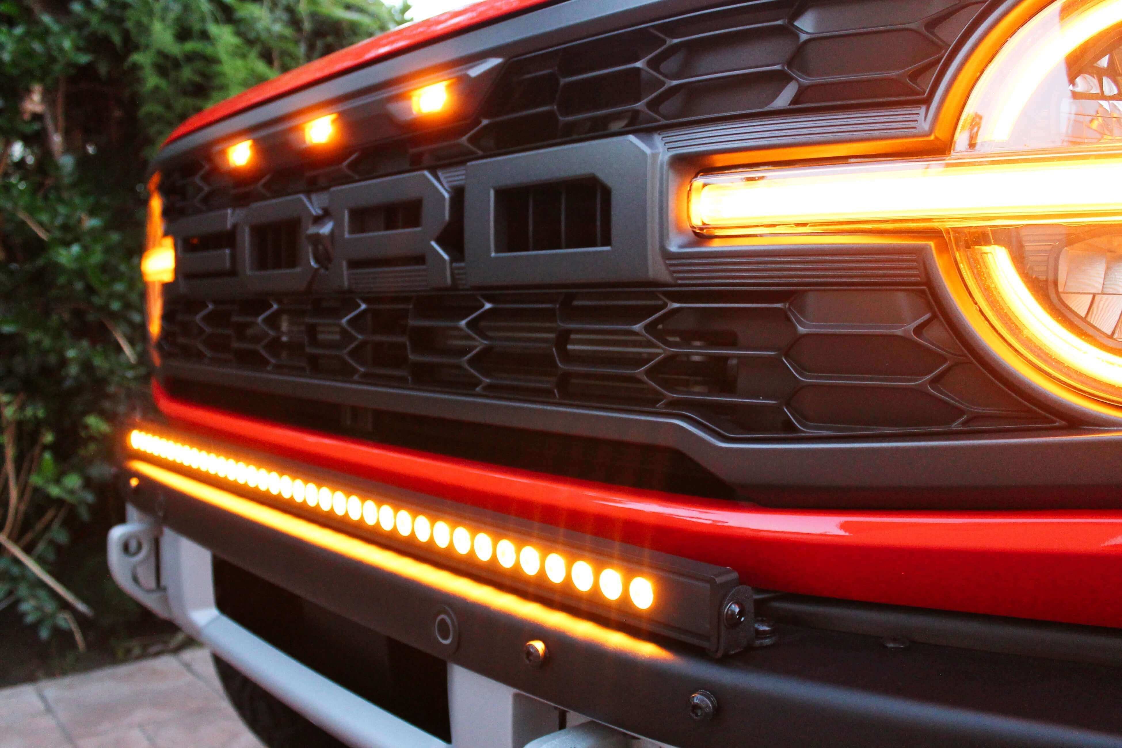 Bronco Raptor Light Bars Install - close-up of glowing orange LED light bars on a Ford Bronco Raptor front grille