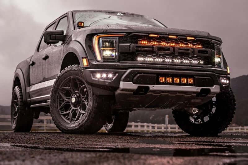 Ford Raptor Gen 3 Lights 2021-2023 off-road truck with upgraded LED light kit on wet road at dusk