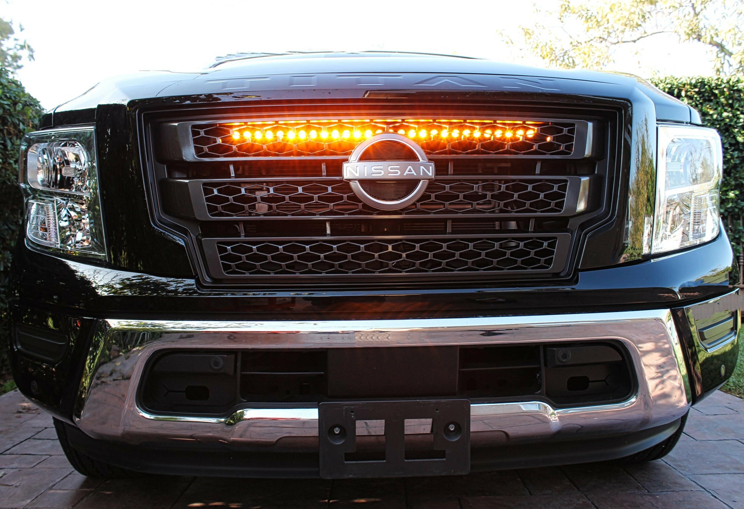 black nissan titan with one led light bar behind the grille in amber color for off roading