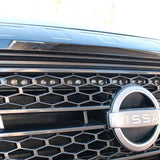 up close view of grille on nissan titan with one led light bar behind the grille in for off roading above the nissan logo