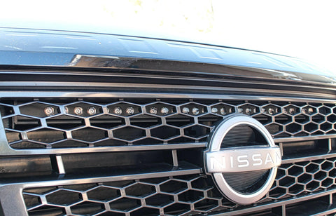 up close view of grille on nissan titan with one led light bar behind the grille in for off roading above the nissan logo
