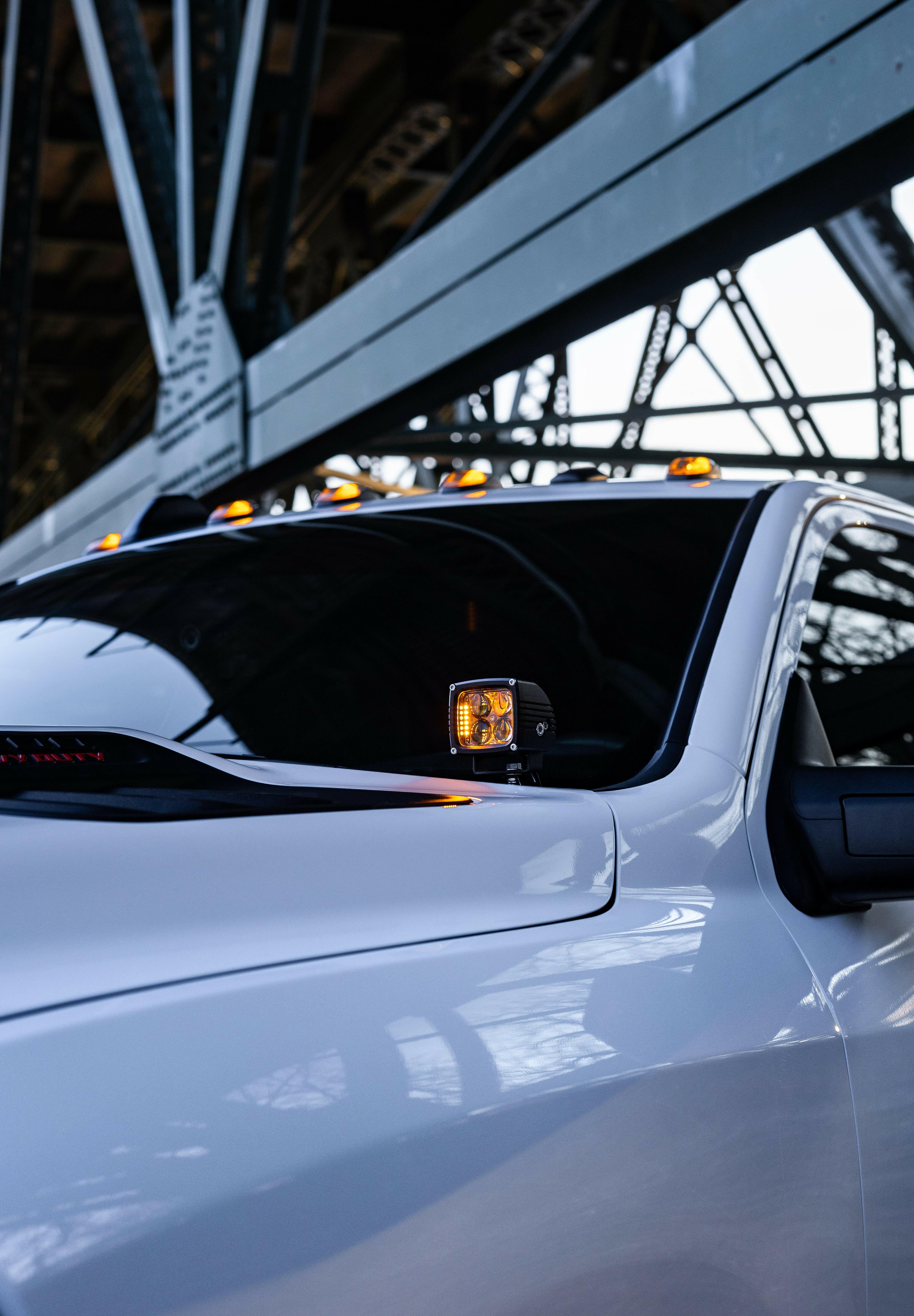 Alt Tag: 2025+ RAM 2500 3500 Ditch Lights with dual color amber DRL glowing on white heavy duty truck under bridge