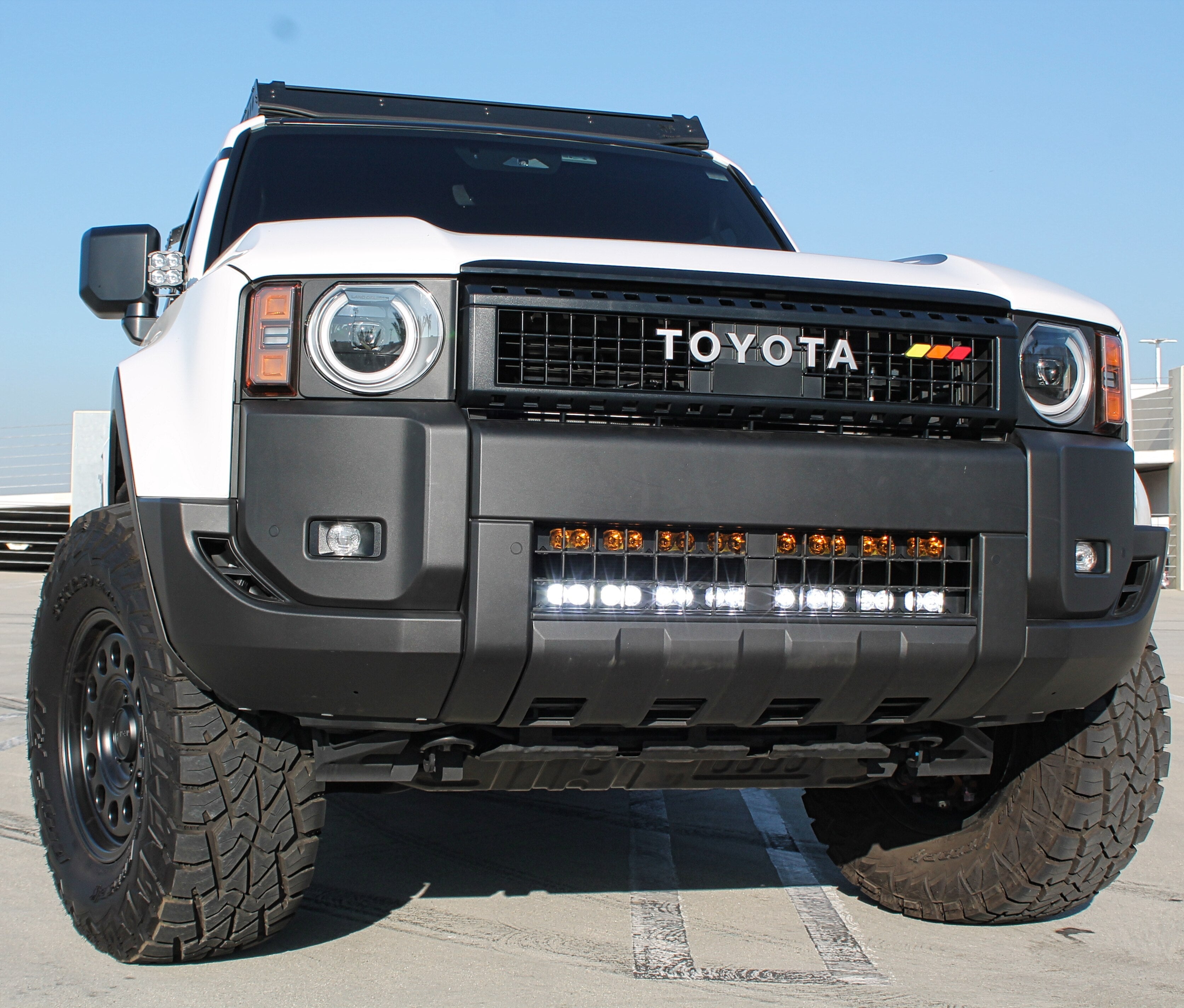 Land Cruiser light bar installed on 2024+ Toyota Land Cruiser behind lower grille, front view with rugged bumper and off-road tires