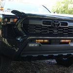 black 2024 toyota tacoma with amber led light bars behind the grille and amber ditch lights
