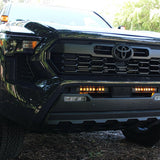 black 2024 toyota tacoma with amber led light bars behind the grille and amber ditch lights