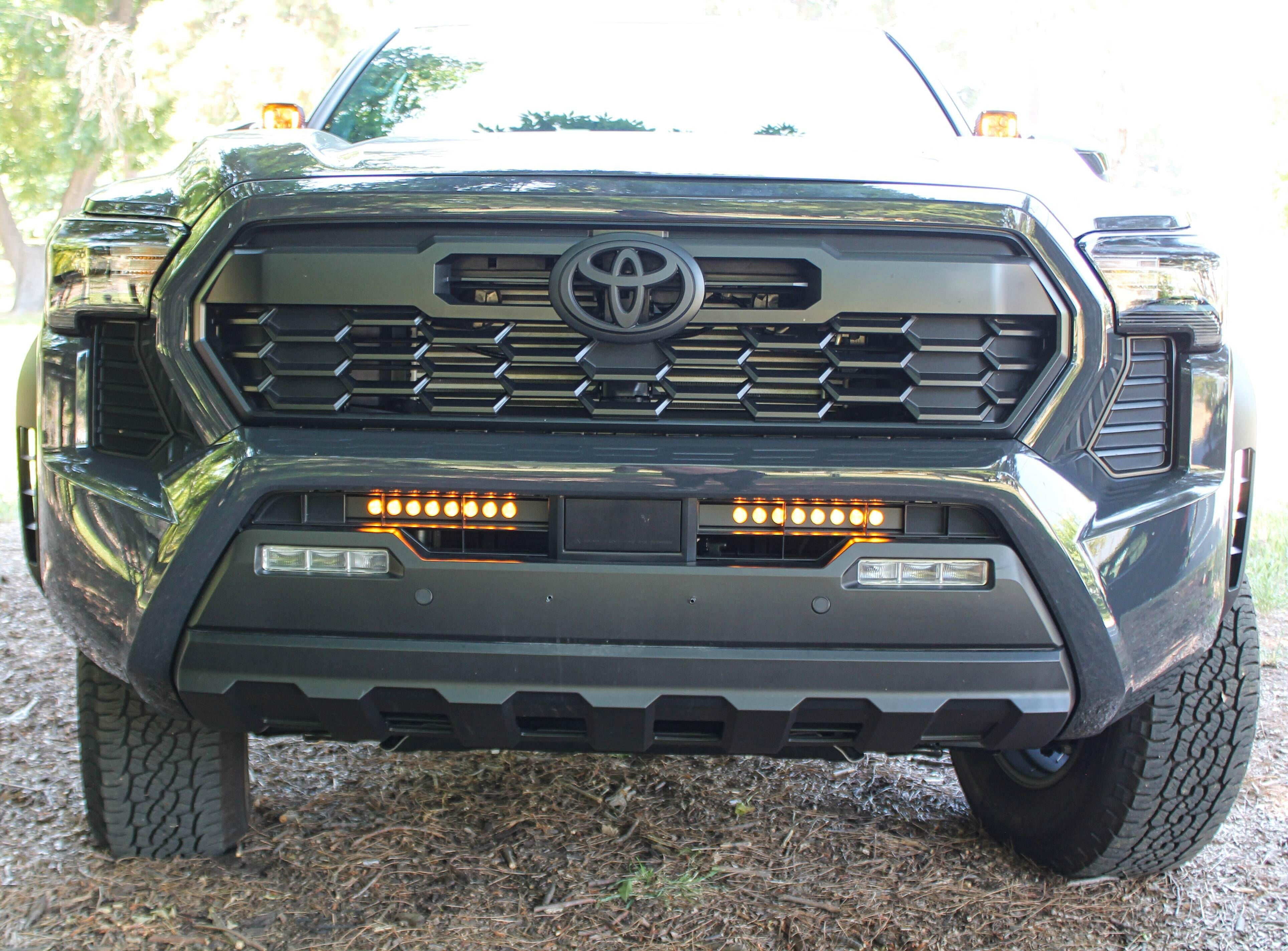 front view gray new toyota tacoma with led light bars behind grille and hood mount kit