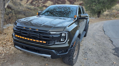 forest green 2024 ford ranger raptor with amber light bar on top of grille and ditch lights