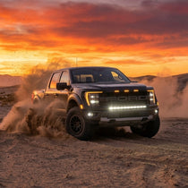 2024 Ford F150 Raptor with light bar driving in desert at sunset, showcasing Ford F150 Raptor Light Bar features.