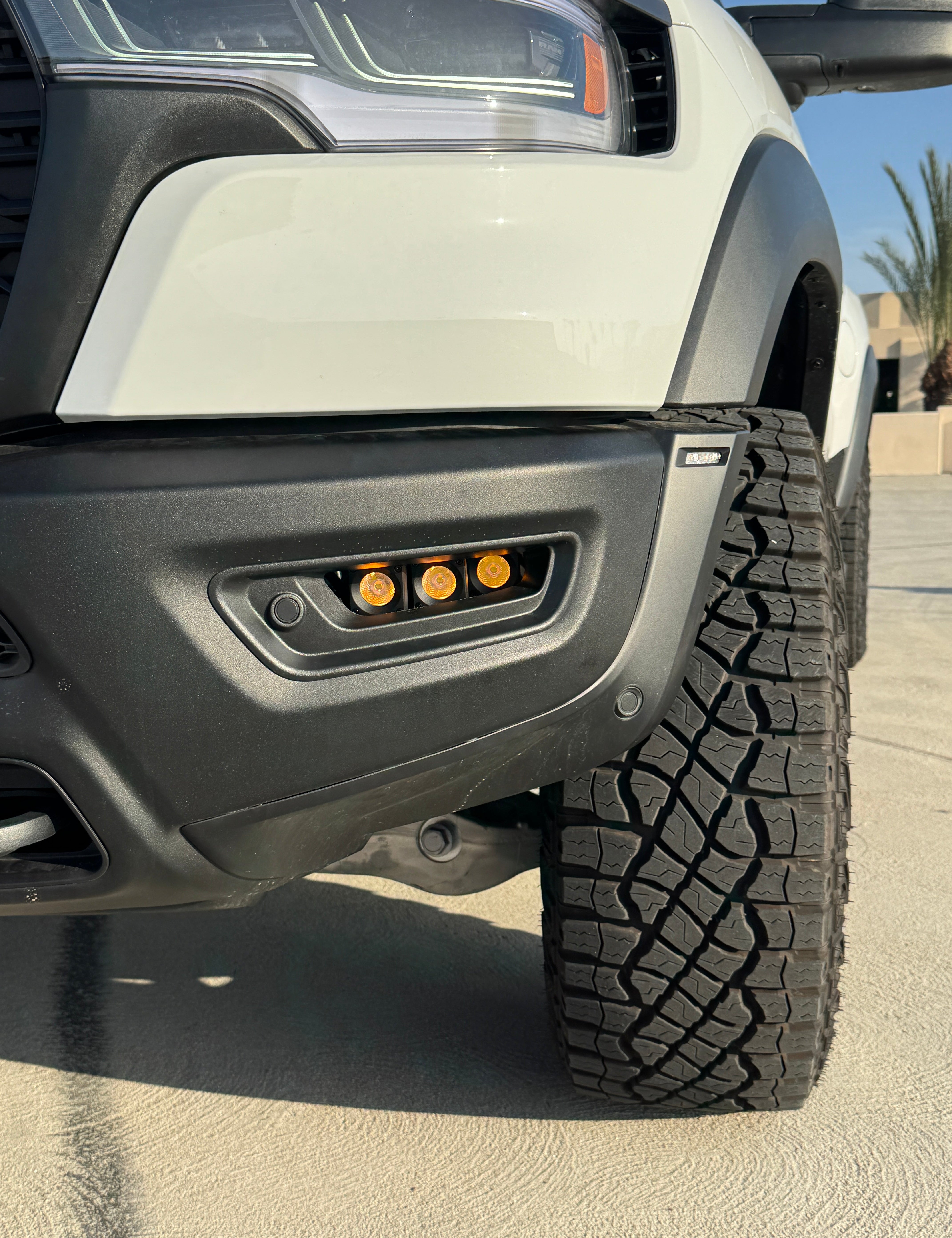 RAM RHO FOG Focus: Close-up of RAM 1500 with fog light kit installed, showcasing orange LED fogs and rugged tire profile