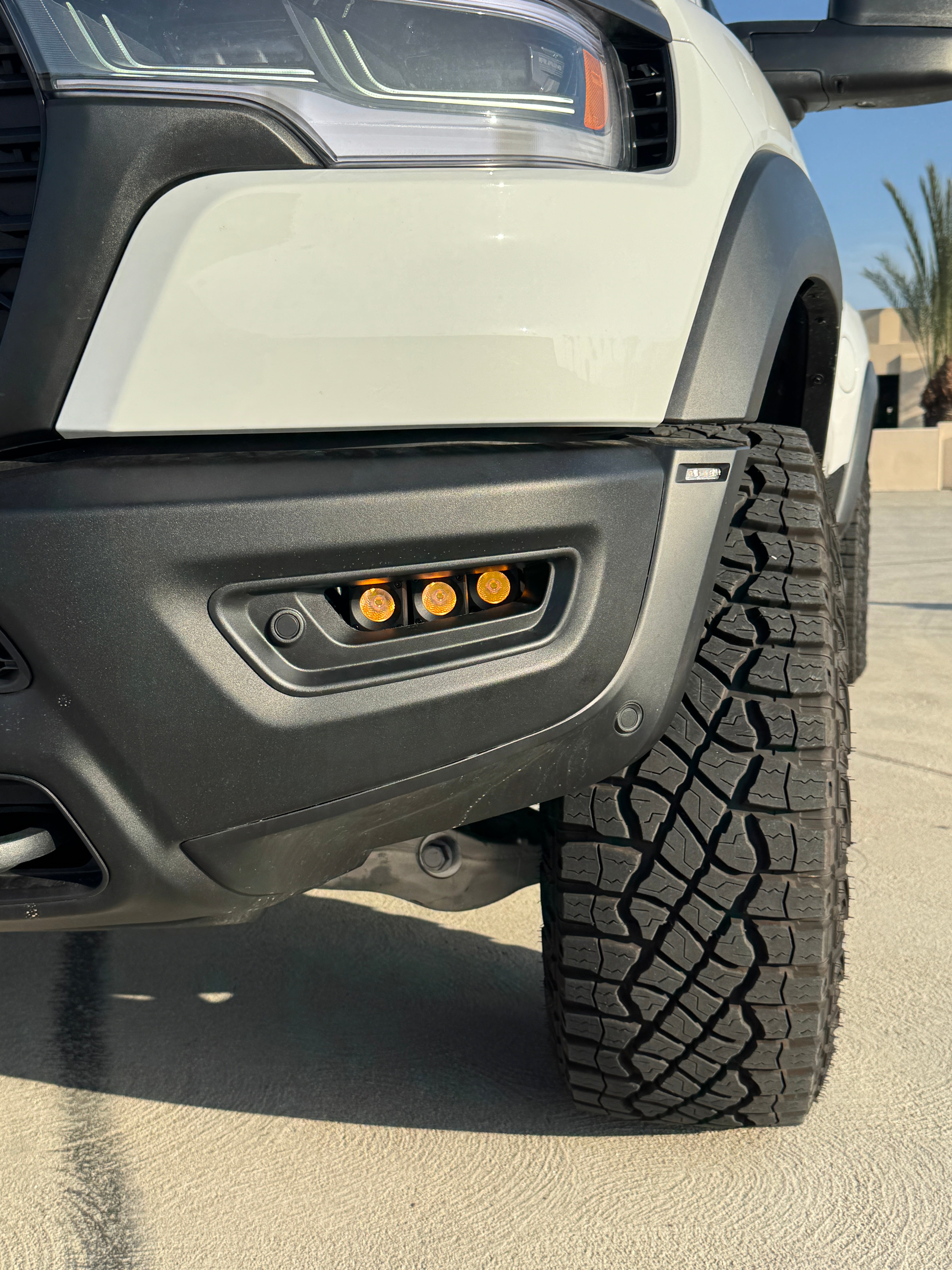 RAM RHO FOG Focus: Close-up of RAM 1500 with fog light kit installed, showcasing orange LED fogs and rugged tire profile