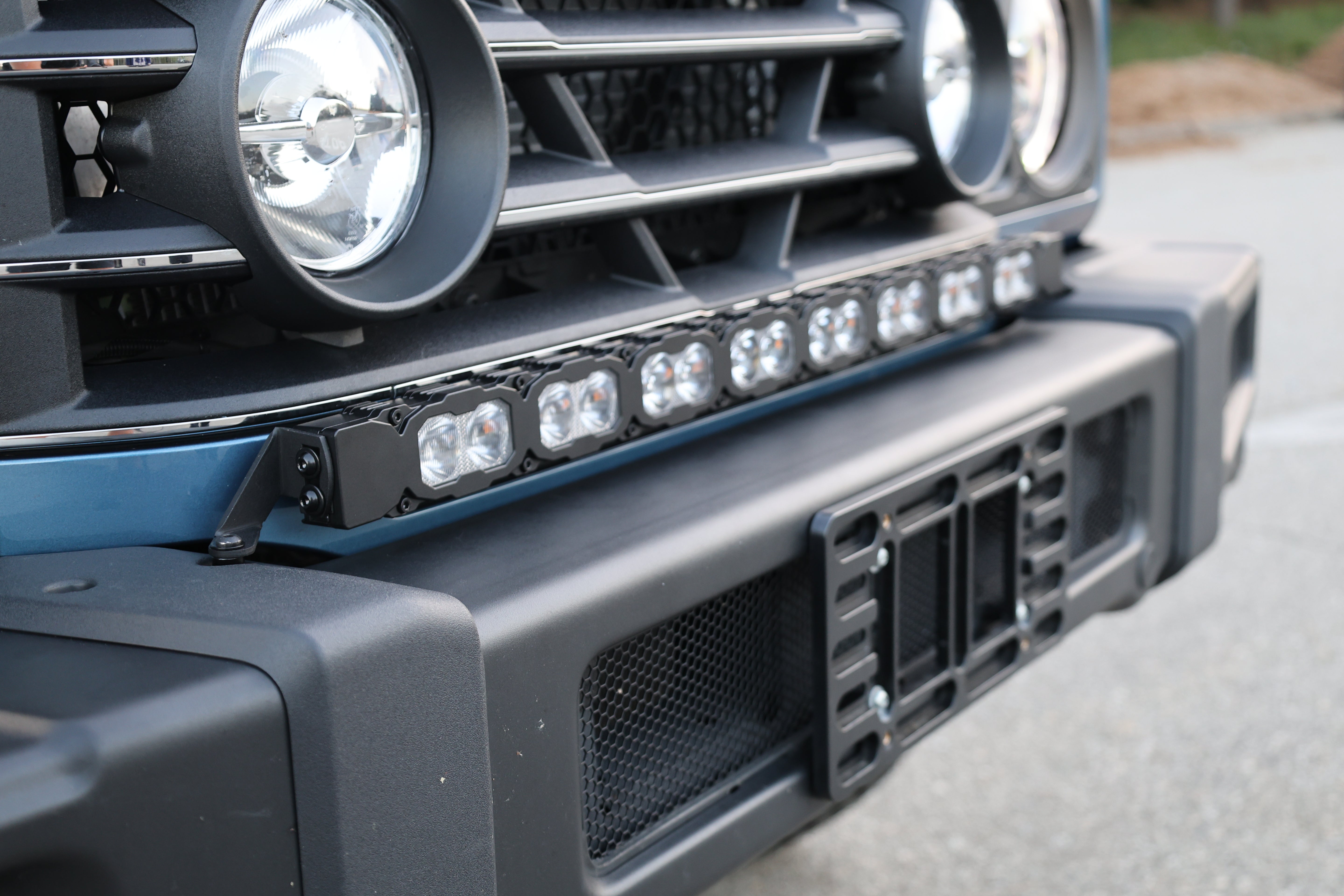 Ineos Grenadier round LED headlight and grille corner with 30in light bar bracket behind the grille