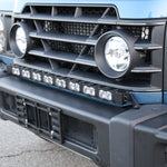 Light-blue Ineos Grenadier honeycomb grille with 30in bumper light bar mounted above, bolt-on kit