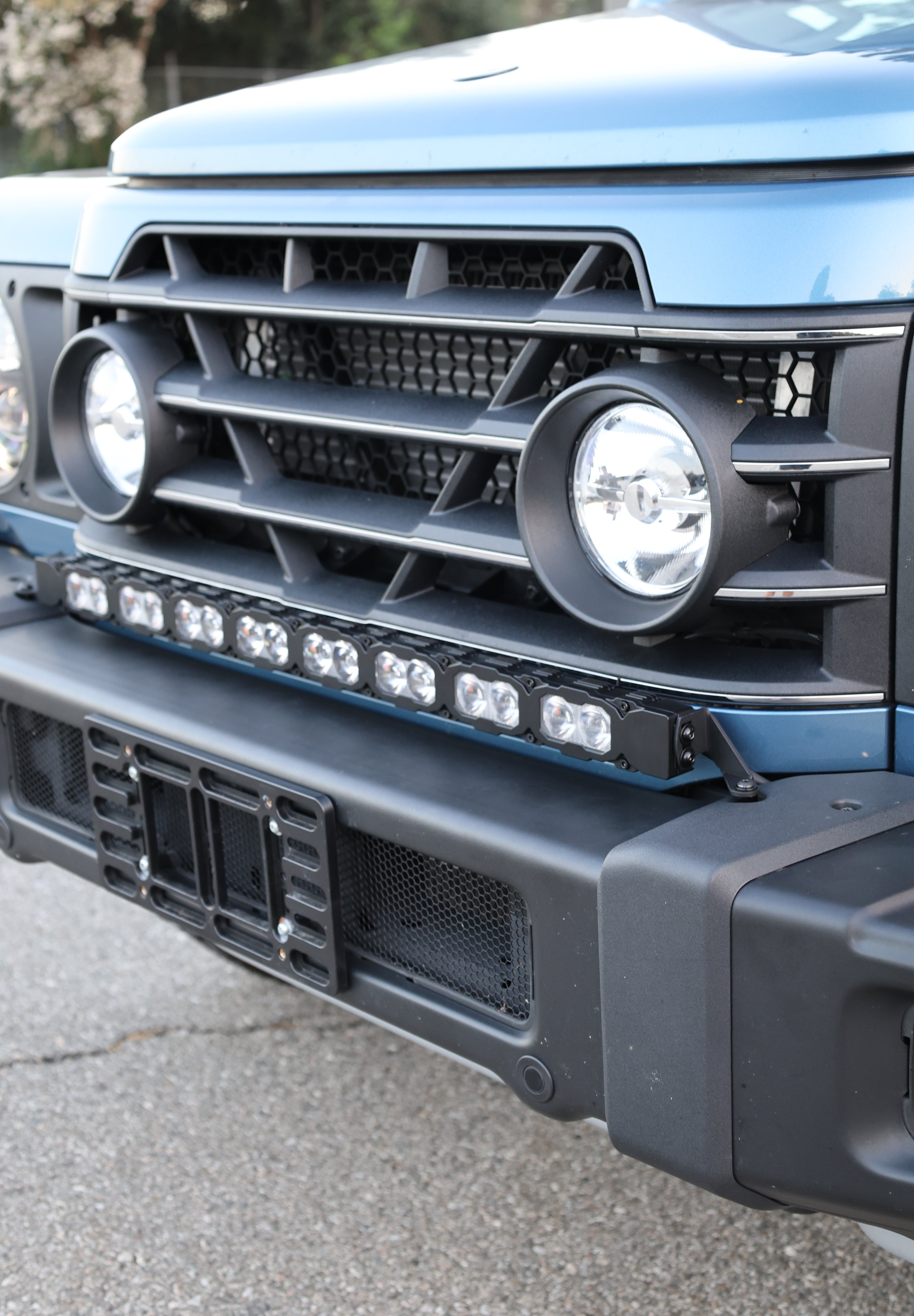 Light-blue Ineos Grenadier honeycomb grille with 30in bumper light bar mounted above, bolt-on kit