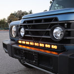 Ineos Grenadier 30in light bar lit in yellow across the front bumper at dusk, off-road driving lights