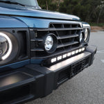 Light-blue Ineos Grenadier hood and windshield with 30in bumper light bar mounted below, daylight