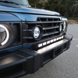 Light-blue Ineos Grenadier hood and windshield with 30in bumper light bar mounted below, daylight