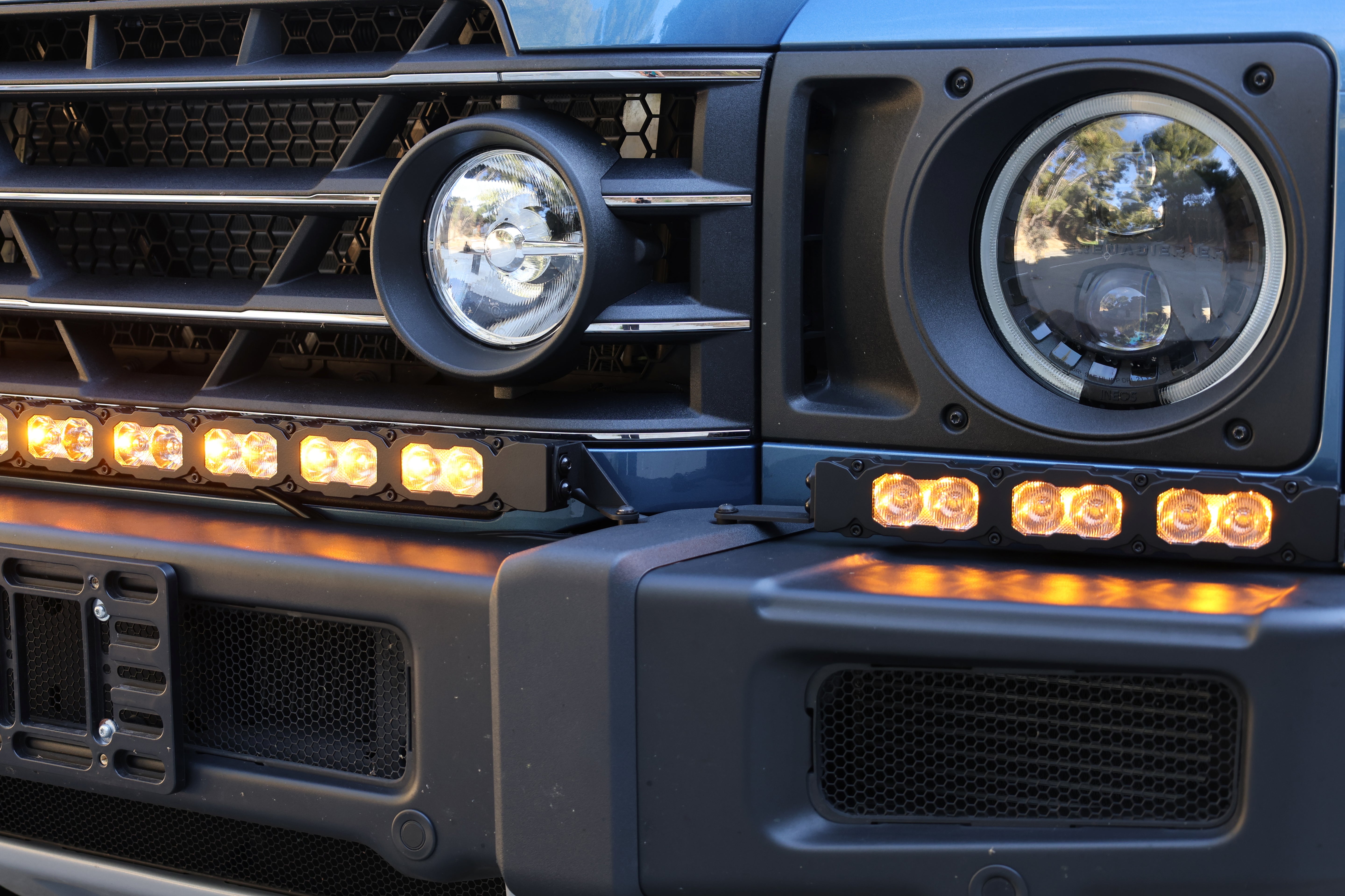 Close-up of the Ineos Grenadier XL light bar kit lit amber, 30in center bar meeting a 12in extension at the corner