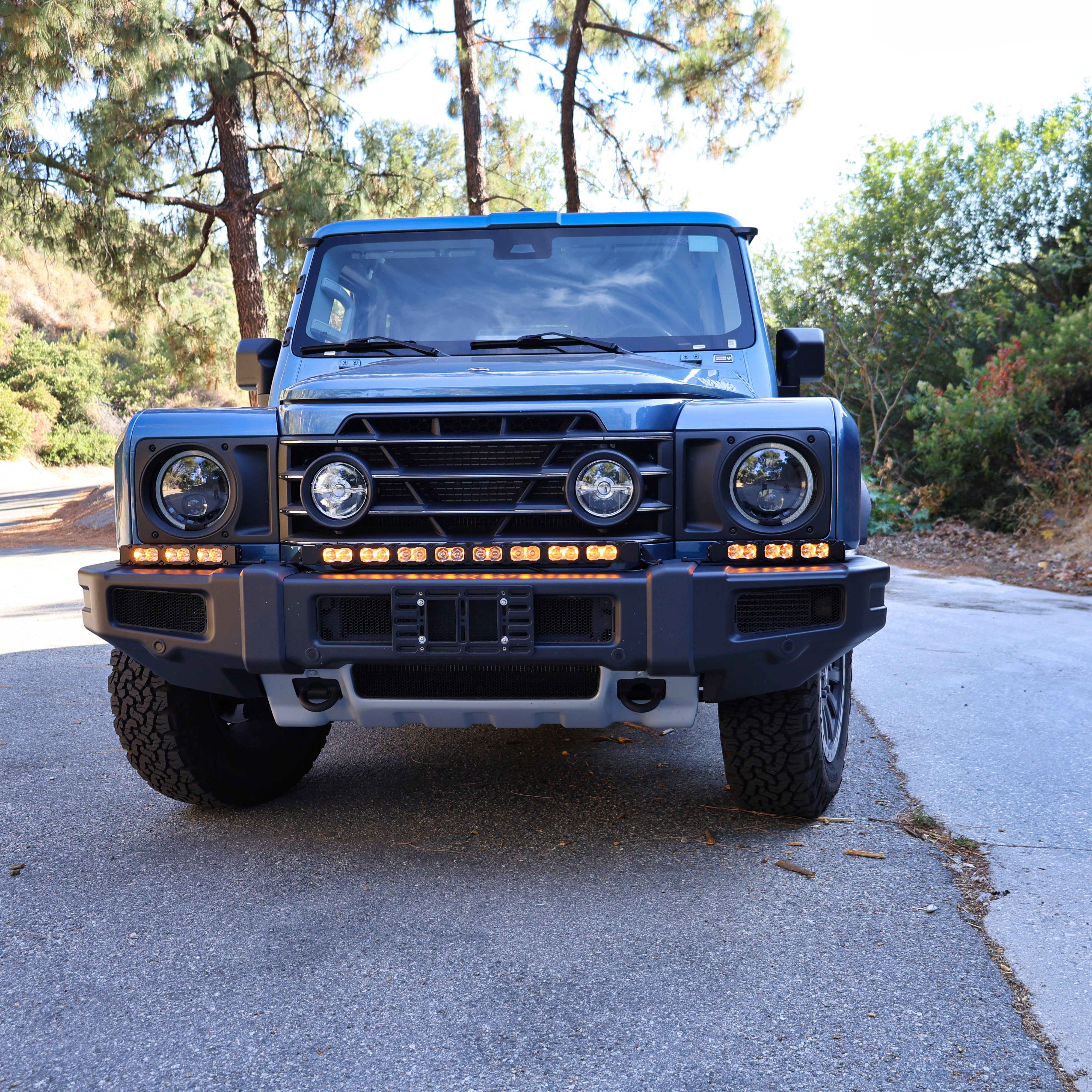 2024+ Ineos Grenadier front view with the full XL light bar kit lit amber across the bumper