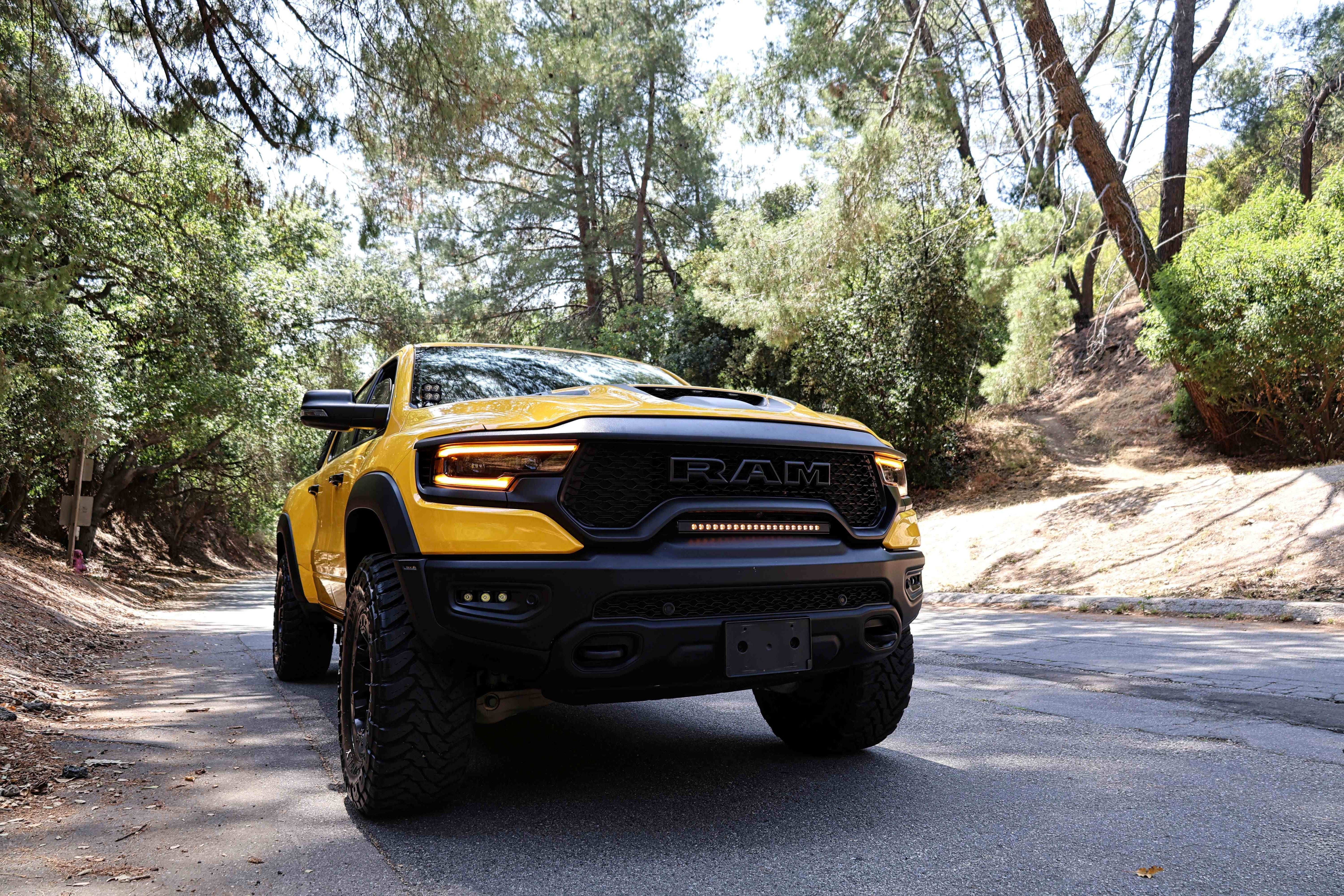 RAM TRX Light bar slim 23in installed in grille opening on yellow 2021-2024 RAM 1500 TRX on forest road