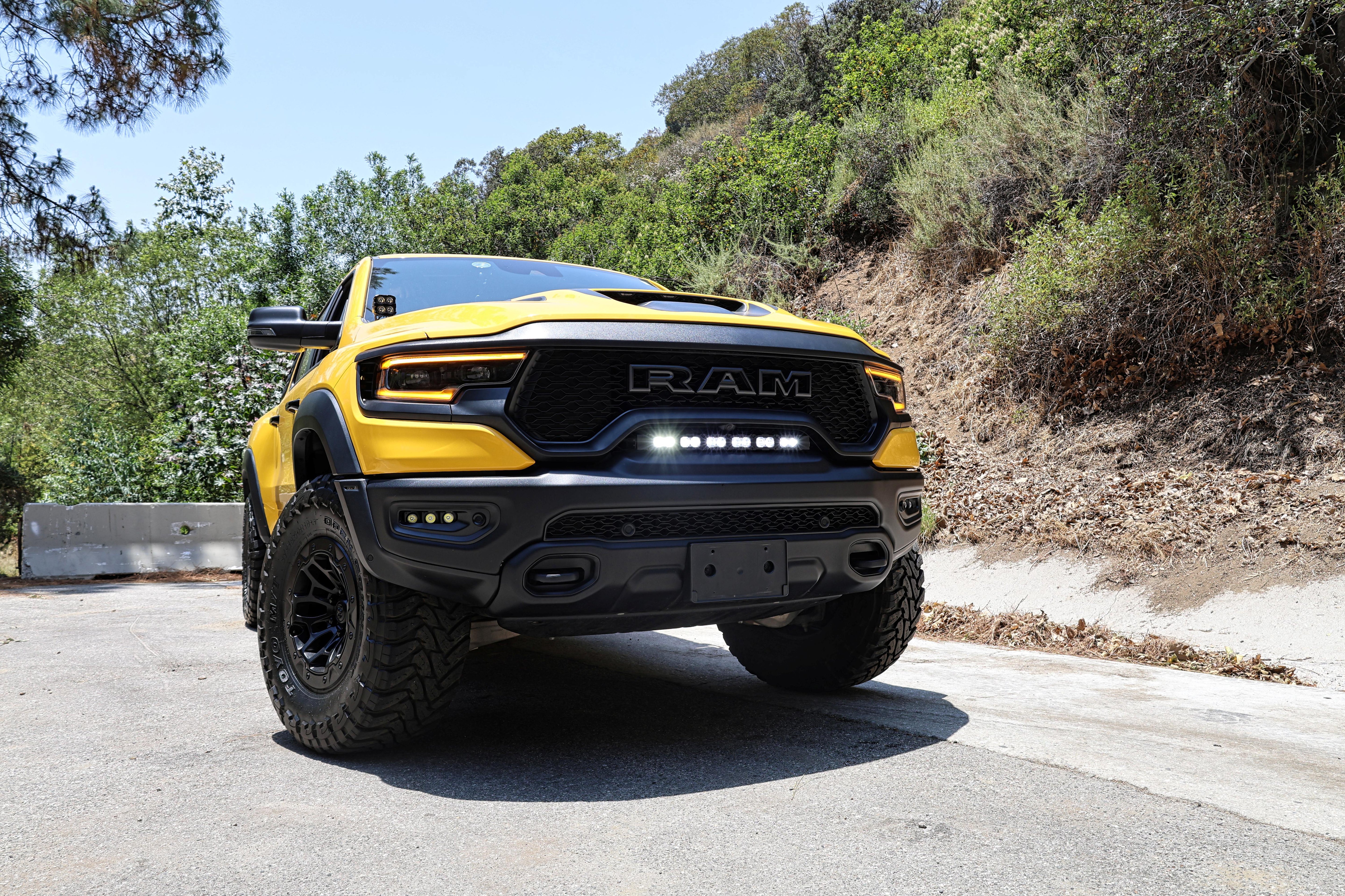 RAM TRX Lightbar 23in PRO installed on yellow RAM 1500 TRX in factory grille opening on forest road