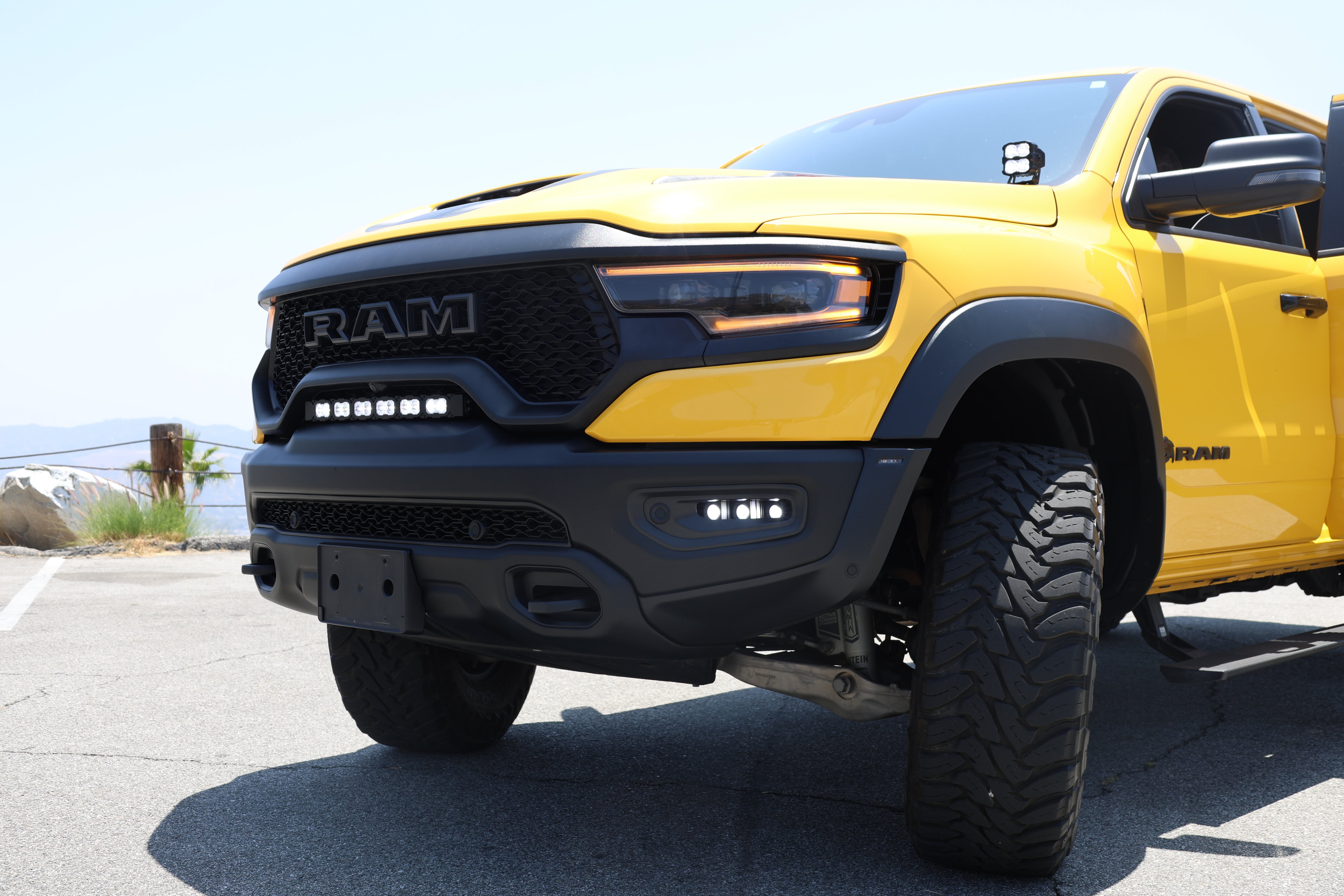 Close-up of the 2019-2024 RAM 1500 TRX fog light kit with three white LED pods lit in the front bumper of a yellow TRX