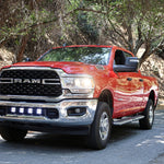 RAM 2500 lightbar Bumper Light kit installed on red 2019-2024 RAM 2500 lower grille LED light pods on forest road