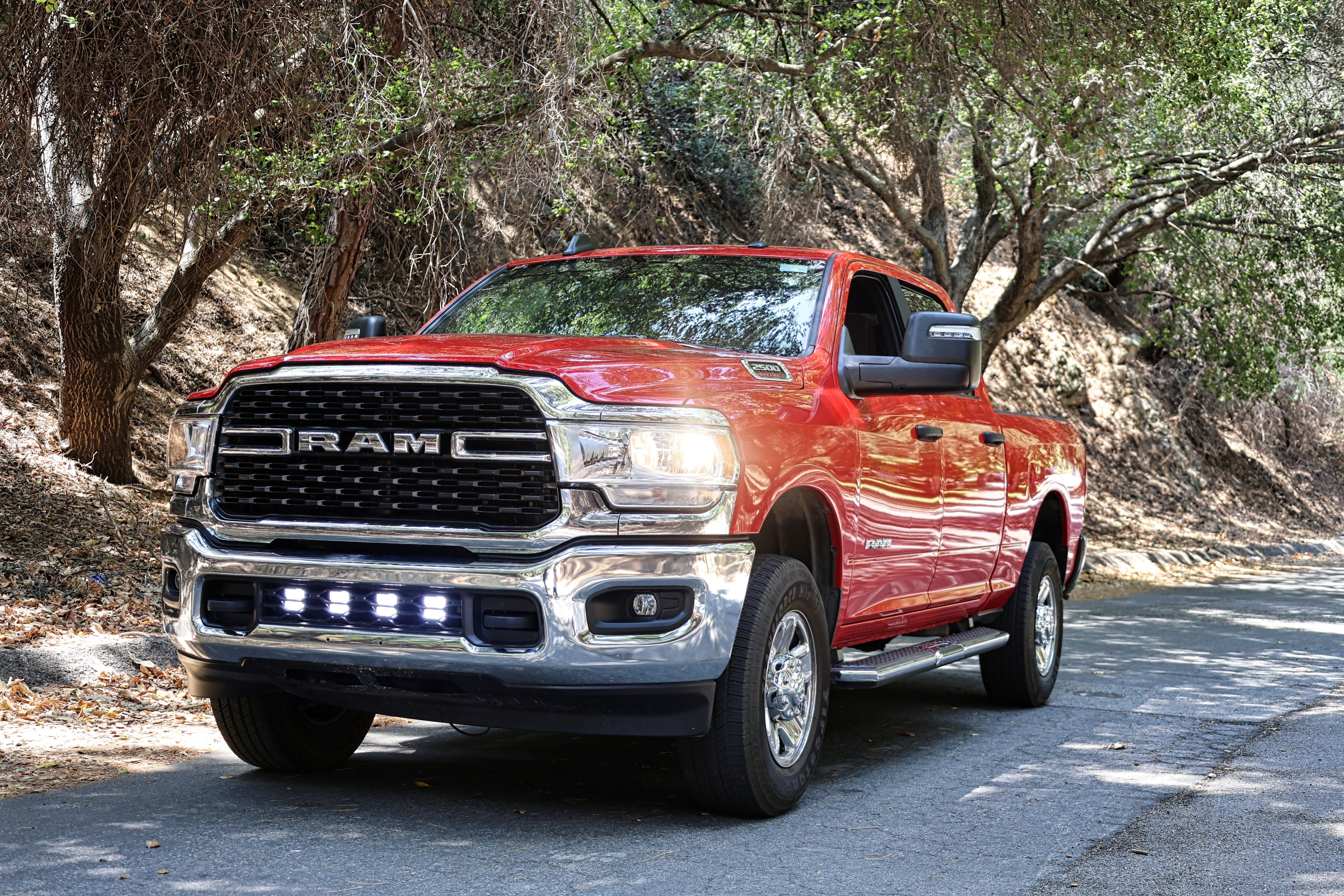 RAM 2500 lightbar Bumper Light kit installed on red 2019-2024 RAM 2500 lower grille LED light pods on forest road