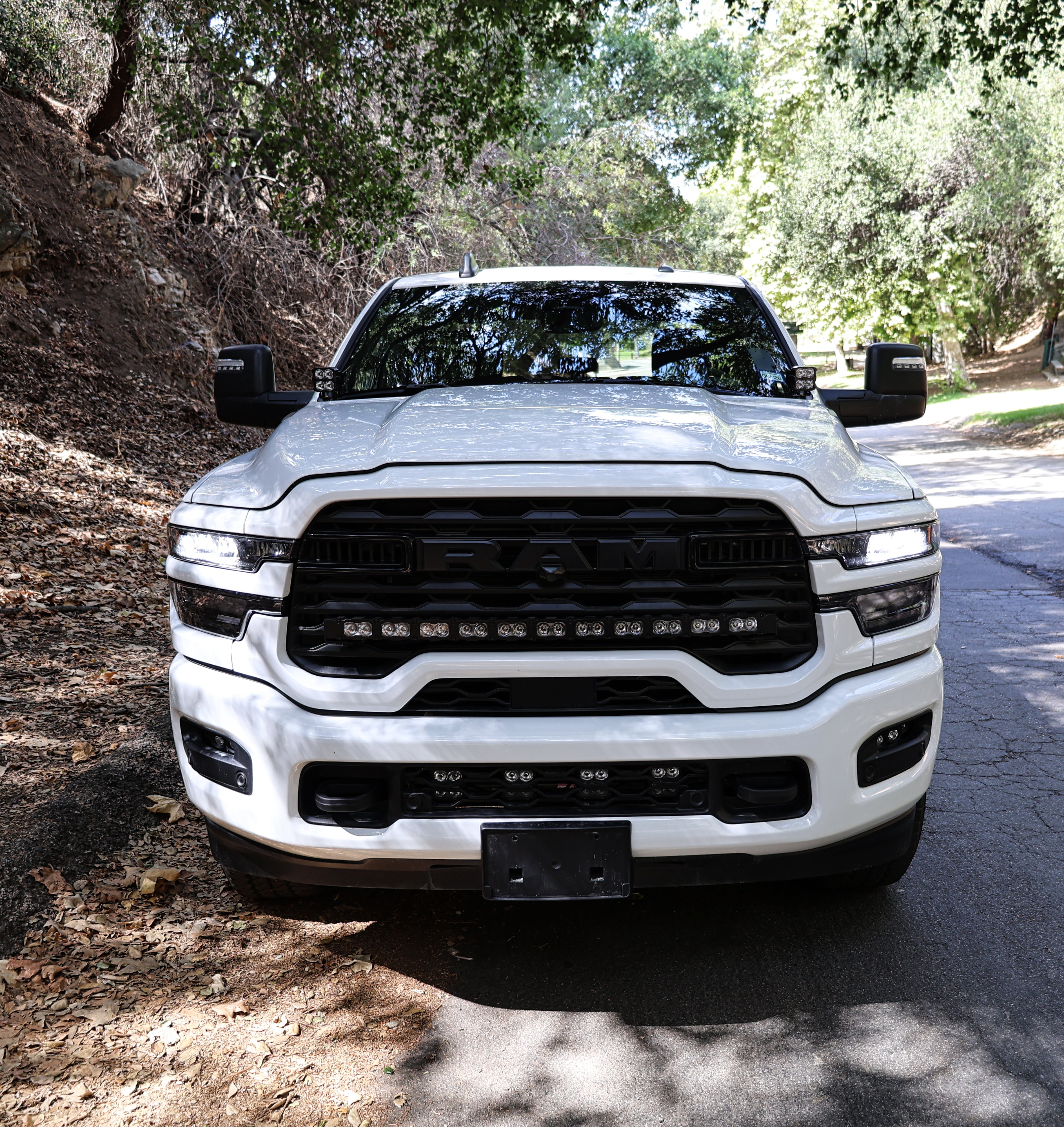 2025+ RAM 2500 Light kit lower grille pods installed on white RAM 2500 truck front view on forest road