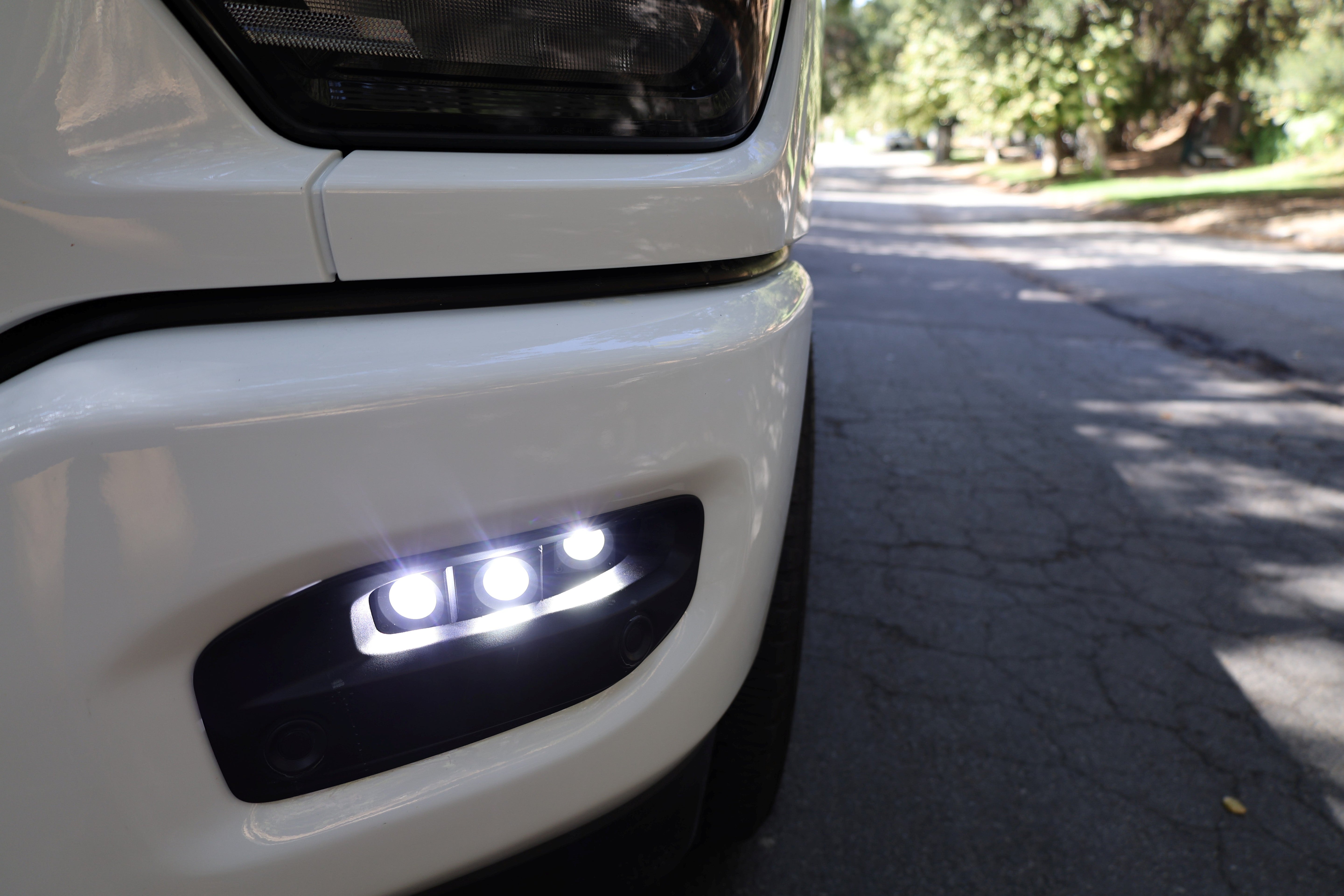 RAM 2500 Fog Light Kit installed on white RAM 2500 truck front bumper with LED fog lights illuminated on street