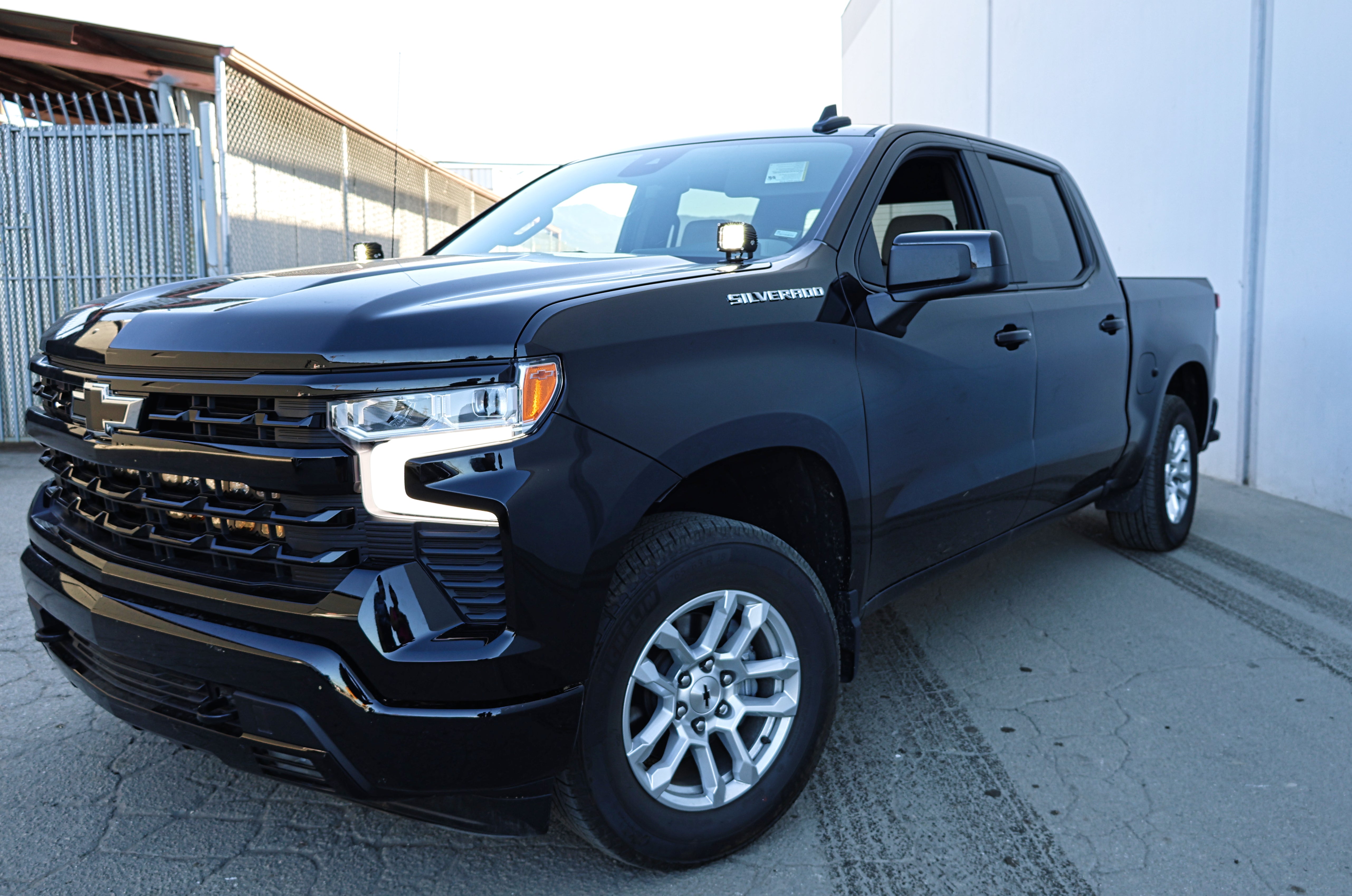 Silverado 1500 ditch lights installed on black 2022+ Chevrolet Silverado 1500 parked outside warehouse