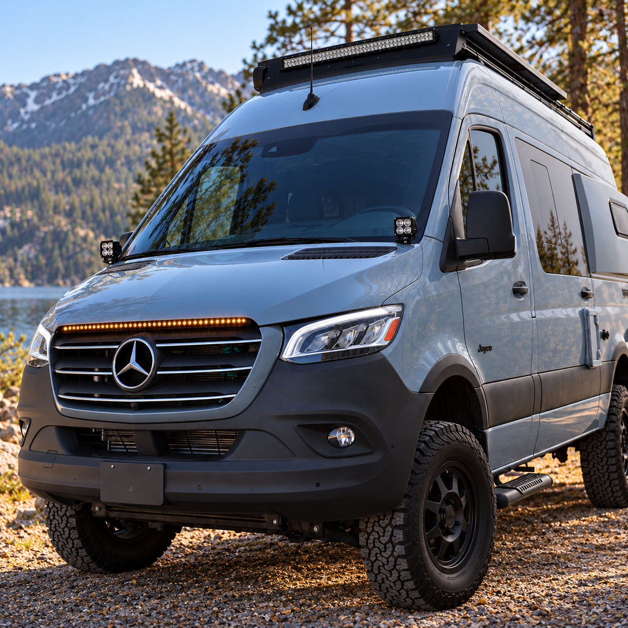 2019+ Mercedes Sprinter 4x4 van at a mountain lake with a 40in SLIM light bar glowing amber on top of the grille