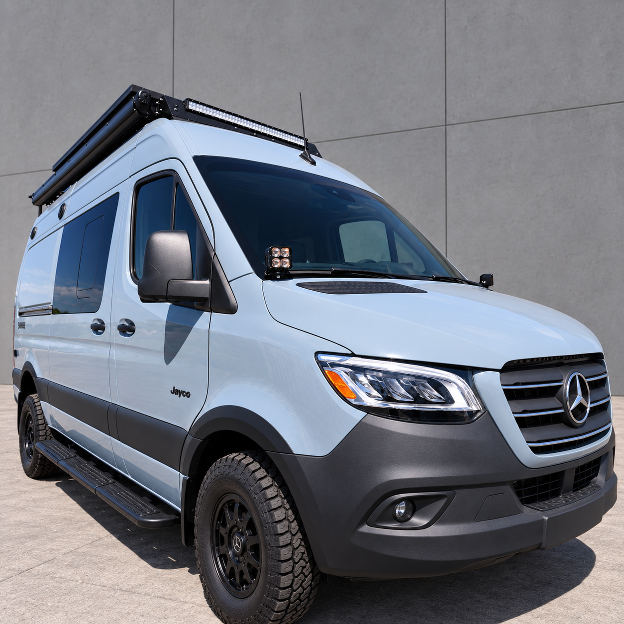 Front three-quarter view of a 2019+ Mercedes Sprinter 4x4 van with ditch light pods at the base of both mirrors