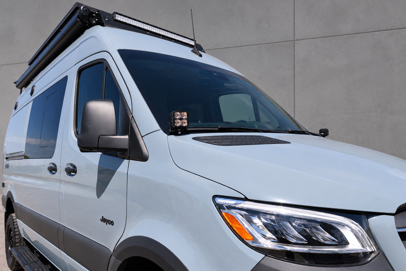 Front three-quarter view of a 2019+ Mercedes Sprinter van with Ditch Lights PRO pods at the base of both mirrors