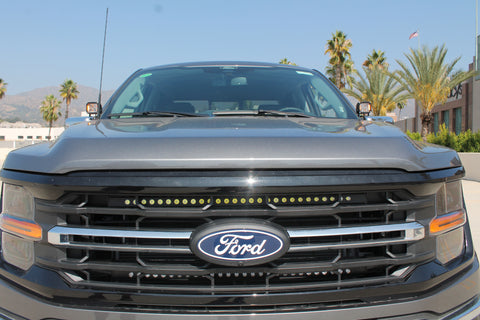 front view grey 2024 ford f150 with amber drl backglow ditch lights and off roading led light bars behind the grille