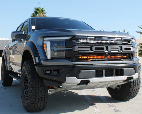 gray 2024 ford raptor with LED light bars behind the grille white and amber for off roading and white LED ditch lights