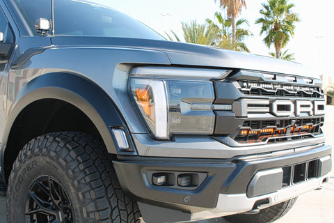 gray 2024 ford raptor with LED light bars behind the grille white and amber for off roading