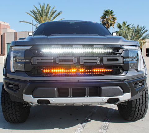 gray 2024 ford raptor with LED light bars behind the grille white and amber for off roading