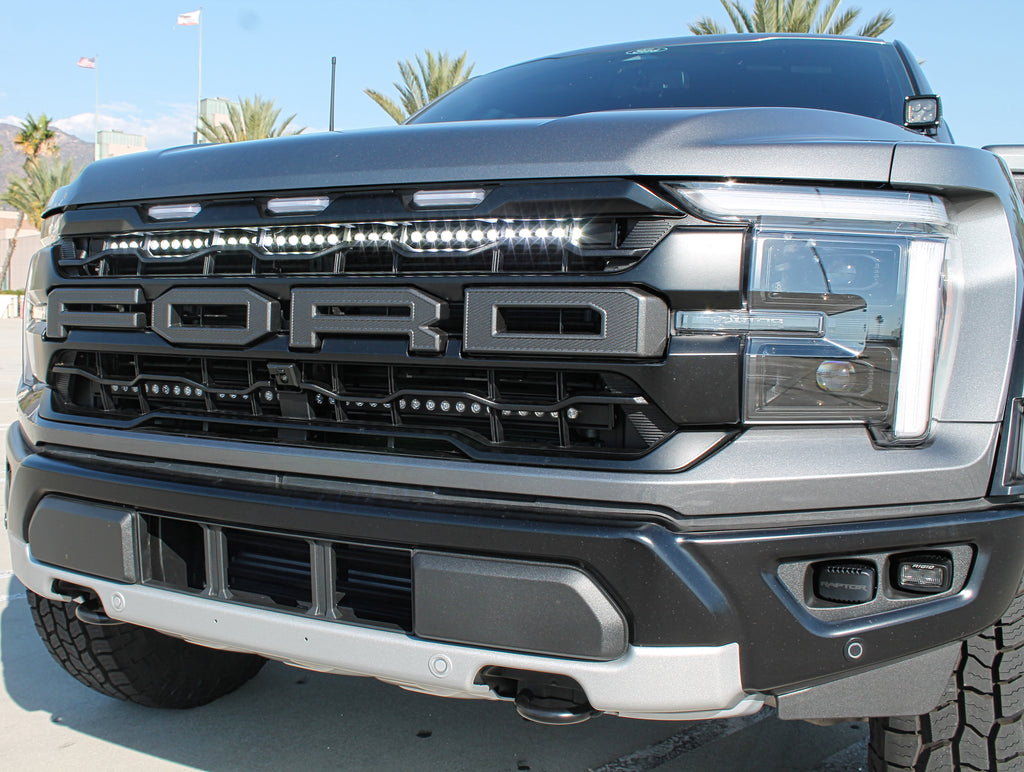 gray 2024 ford raptor with white LED light bar behind the grille for off roading and ditch lights