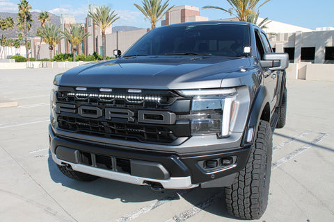 gray 2024 ford raptor with white LED light bars behind the grille and ditch lights for off roading