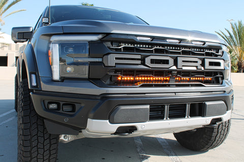 gray 2024 ford raptor with LED light bars behind the grille amber for off roading