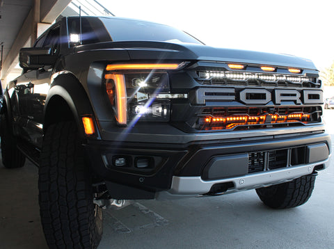 gray 2024 ford raptor with LED light bars behind the grille white and amber for off roading and ditch lights