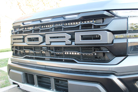 up close view of grille on gray 2024 ford raptor with LED light bars behind the grille for off roading