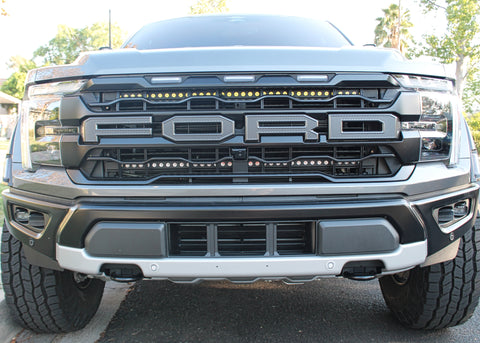 gray 2024 ford raptor with LED light bars behind the grille for off roading