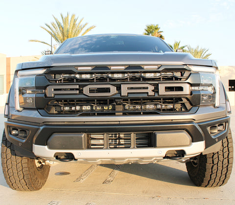 front view of gray 2024 ford raptor gen 3 with 2 light bars behind the grille and ditch lights for off roading