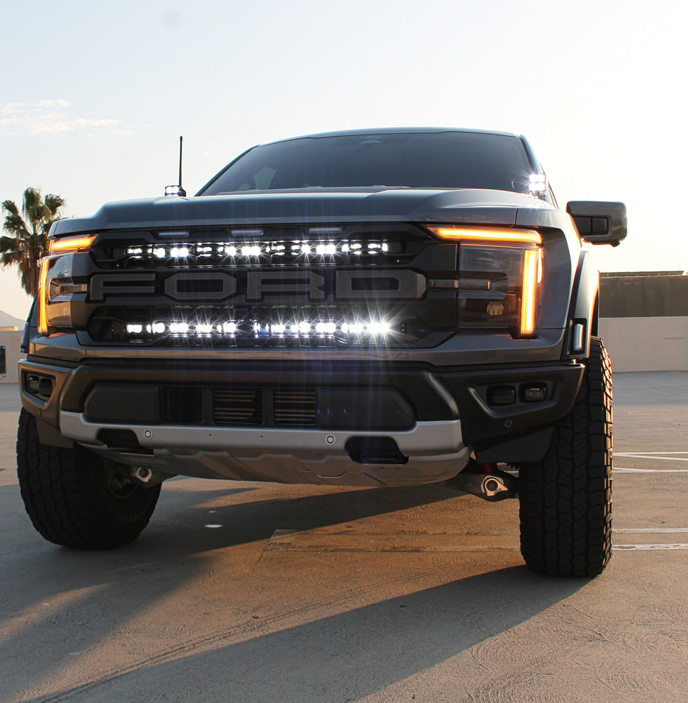 gray 2024 ford raptor gen 3 with 2 light bars white behind the grille and ditch lights for off roading