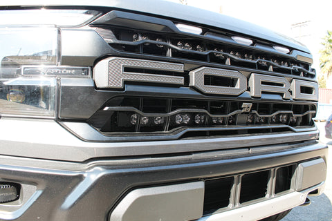 up close grille of gray 2024 ford raptor gen 3 with 2 light bars behind the grille 