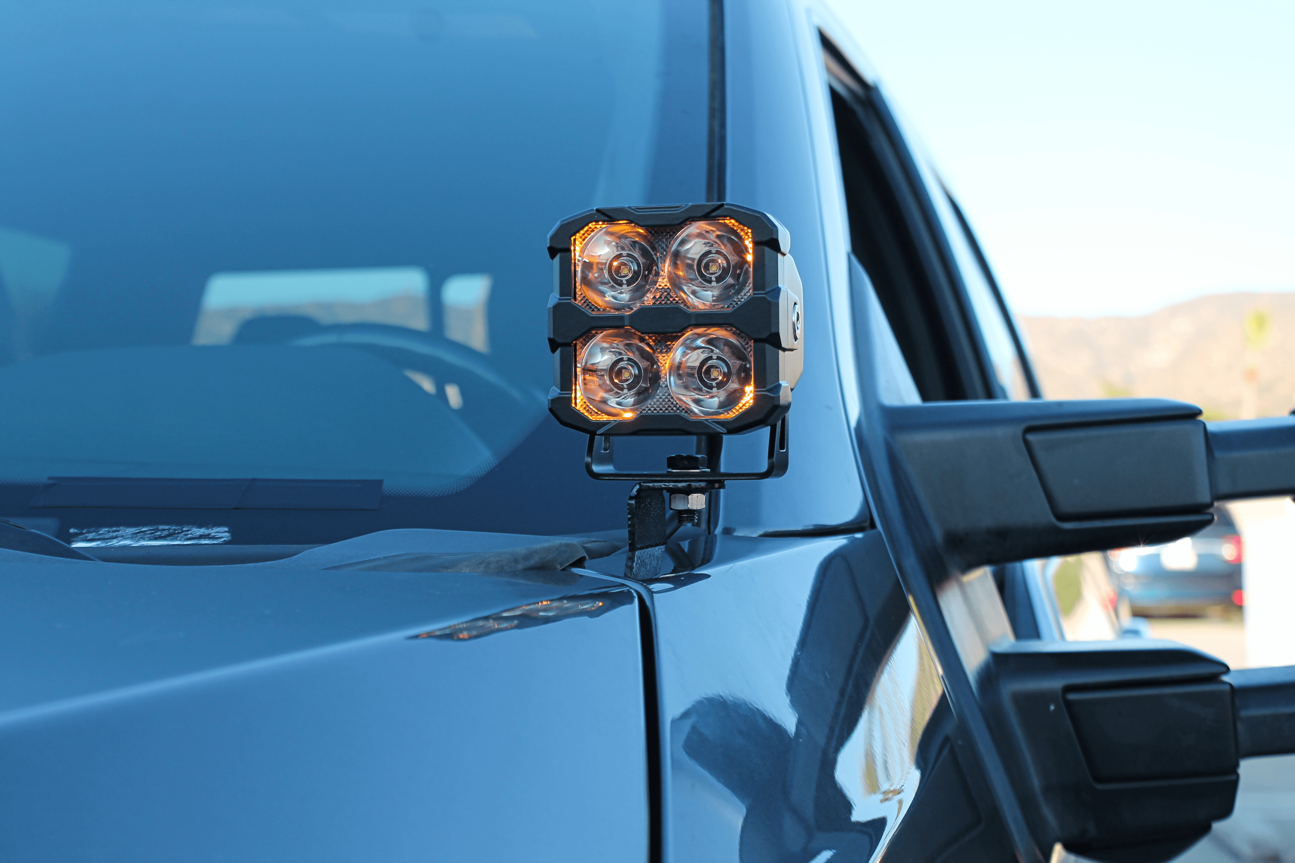 Ford Super Duty ditch lights shown on a rugged pickup, dual amber LEDs mounted on the hood for off-road visibility