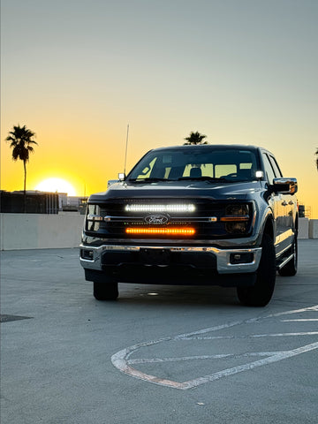 black 2024 ford f150 with white and amber LED light bars behind the grille and white hood mount kit, ditch lights